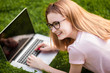 © Smeilov - Girl in glasses with laptop lying on the lawn