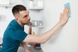 © Syda Productions - household and people concept - man with cloth cleaning wall at home kitchen