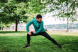 © bnenin - Young man in sportswear doing stretch exercises outdoors.