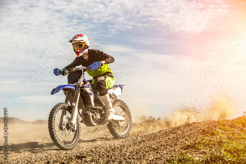 Foto  Professional Motocross Motorcycle Rider Drives Through Smoke and Mist Over the Dirt Road Track
