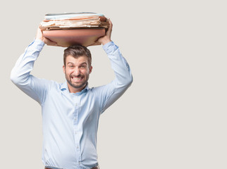 young handsome man holding a tower of documents or files wearing a blue t shirt,  boring expression . person isolated against monochrome background