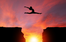 Silhouette Of Girl Leaping Over Cliffs With Sunset Landscape