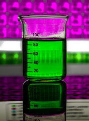 laboratory glassware , a beaker containing a green liquid on a reflecting surface