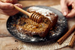 © Stasique - Close up of woman hands pouring honey on fresh brown nut cake. Delicious dessert with cinnamon complement.