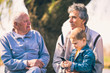 © Mediteraneo - Two senior men and grandson using smart phone in the park