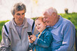© Mediteraneo - Two senior men and grandson using smart phone in the park