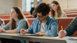 © Gorodenkoff - Hispanic Young Man Among His Fellow Students in the Classroom. Young Bright People Listening to a Lecture and Take Notes while Studying at the University.