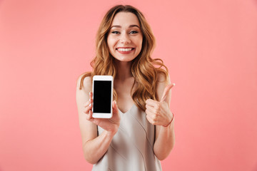 Poster - Happy brunette woman in pajamas showing blank smartphone screen