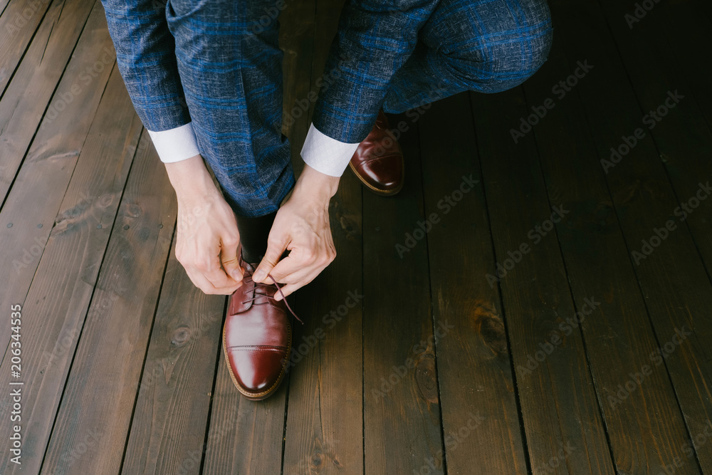 Man wearing a blue suit putting his brown shoes on. Hands and shoe close-up  Stock Photo | Adobe Stock