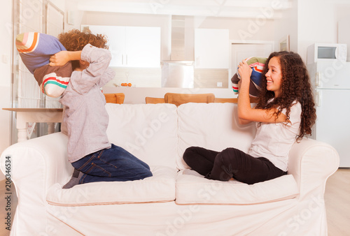 Teenage Boy And Girl Pillow Fighting On The Couch Buy This Stock