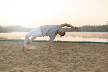 Wall Mural - Athletic capoeira performer workout training on the beach sunris