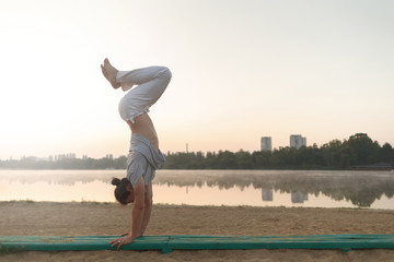 Wall Mural - Young athletic man doing yoga poses near the lacke