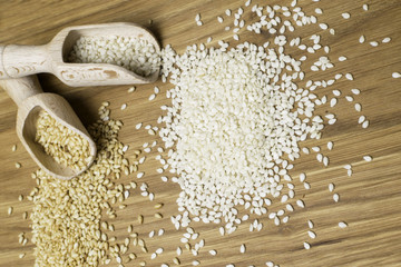 sesame seeds on the wooden background. Two type of sesame seeds in wooden spoon.