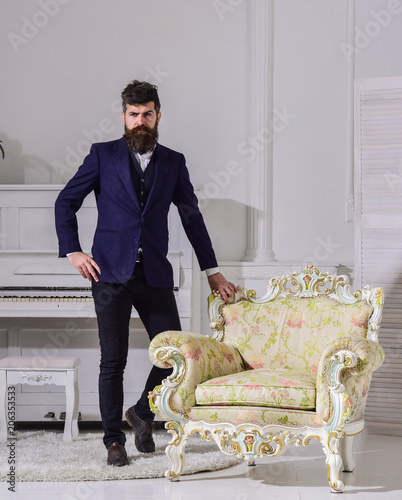 Fashion And Style Concept Man With Beard And Mustache Wearing Classic Suit Stylish Fashionable Outfit Macho Attractive And Elegant On Serious Thoughtful Face Standing Near Old Fashioned Armchair Buy This Stock