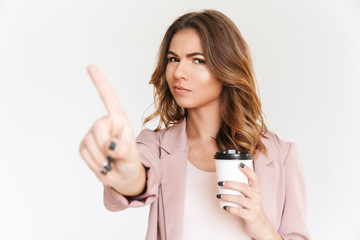 Poster - Displeased lady standing isolated holding coffee showing stop finger gesture.