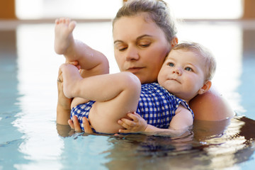 Wall Mural - Happy mother swimming with cute adorable baby girl daughter in swimming pool spending spa vacations