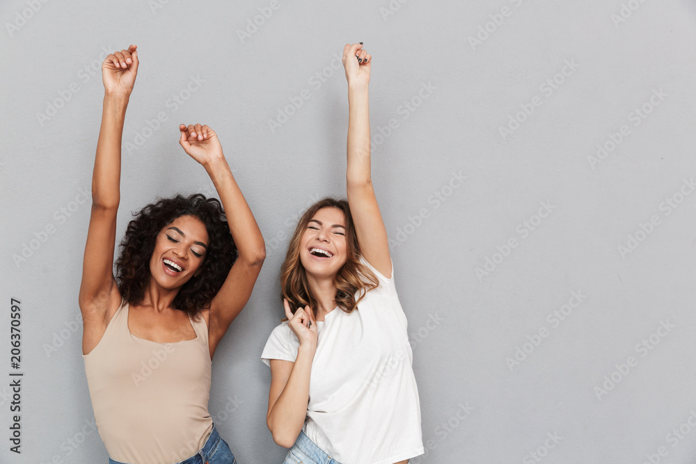 Portrait of two happy young women dancing - obrazy, fototapety, plakaty 