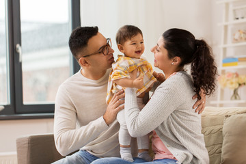 Wall Mural - family, parenthood and people concept - happy mother, father with baby daughter at home