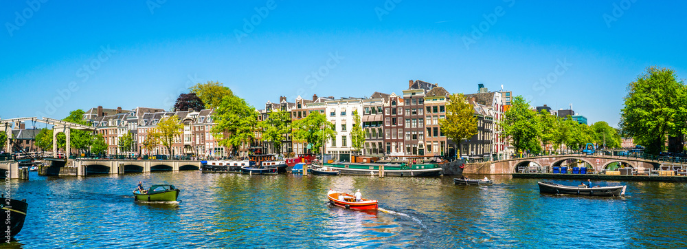 Amsterdam, May 7 2018 - view on the river Amstel filled with small boats and the Magere brug (skinny bridge) in the background on a summer day - obrazy, fototapety, plakaty 