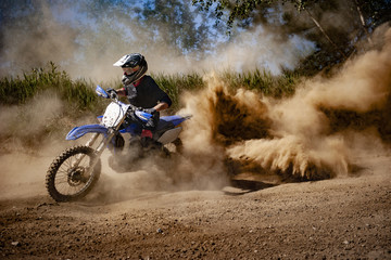 Motocross rider creates a large cloud of dust and debris