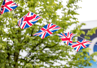 Union Jack bunting flapping in the breeze celebrating British event outside with trees in the background