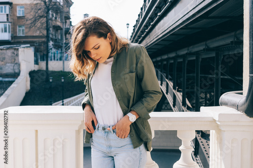 Fotografía Young woman with wavy hair standing next to a bridge