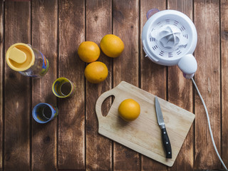 Wall Mural - morning preparation of orange juice concept with juicer knife and glasses on a wooden table