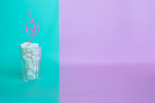 Glass Full Of Sugar Cubes On A Pink And Blue Background With Copy Space- Unhealthy Diet Concept.