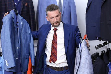 Canvas Print - Handsome man choosing suit in shop