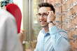 © New Africa - Man trying on glasses in optical store. Ophthalmologist prescription