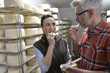© goodluz - Couple of cheese makers testing bite of cheese in cellar