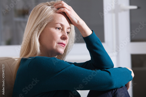 Fotografía Sad depressed middle aged woman at home sitting on the couch, looking down and t