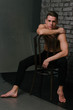 © Skripnik Olga - Casually handsome. Studio shot of handsome young man sitting on the chair and looking at camera. bare chest