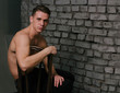 © Skripnik Olga - Casually handsome. Studio shot of handsome young man sitting on the chair and looking at camera. bare chest