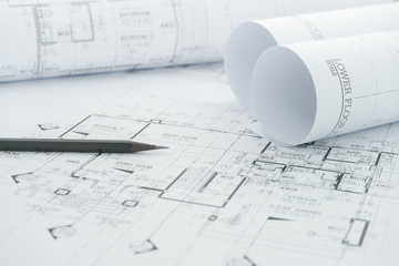 architects workplace - architectural blueprints with measuring tape and black pencil on table.