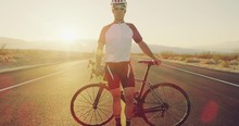 Portrait Of Healthy Cyclist Athlete Standing On Isolated Desert Road At Sunset With Lens Flare 