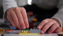 A Young Child Plays In The Constructor. Game Of The Children's Designer. Colored Cubes. Small Arms Are Connected Cubes With Each Other