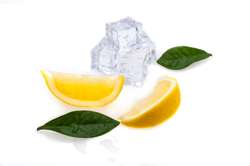 Cubes of cold ice, two slices of fresh yellow lemon and green leaves on white isolated background.