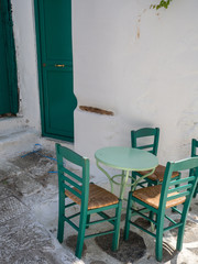 Wall Mural - A green metallic table with four green wooden chairs and a green door