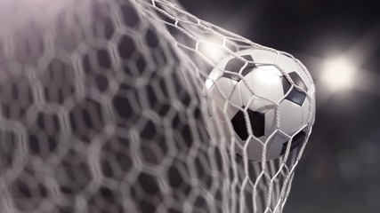 Soccer ball flies into the net on a stadium with flash lights. The movement at the beginning is accelerated then slowly