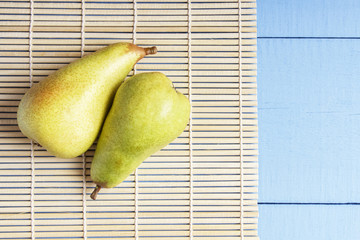 Vegetarian food from natural organic fruits. Fresh pears on bamboo mat for healthy nutrition. Top view on wooden table with copy space