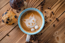 Cat Foam Face Of Latte Art Coffee In Cup With Scattered Coffee Beans And Biscuits On Old Wooden Table