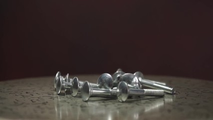 Aufkleber - Bolts rotating on a metal table and red background. 