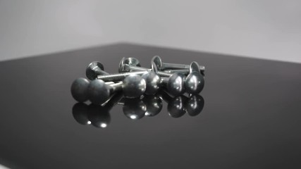 Aufkleber - Bolts rotating on a glass table and black background. 