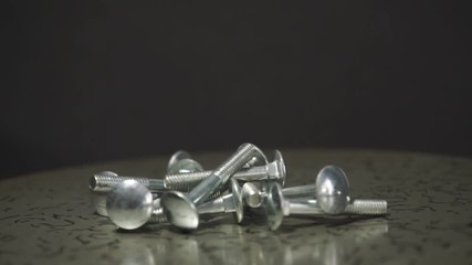 Aufkleber - Bolts rotating on a metal table and black background. 