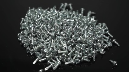 Aufkleber - screws rotating on a glass table and black background. Seamless loop.
