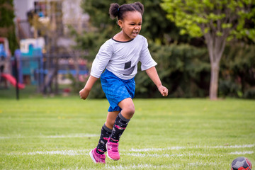 Wall Mural - A young girl is learning how to play soccer	