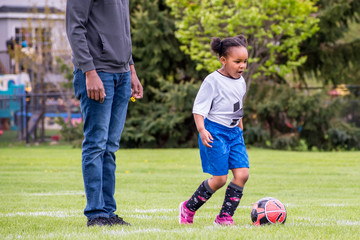 Wall Mural - A young girl is learning how to play soccer	