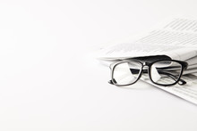 Pile Of Newspapers With Eyeglasses, On White Background With Copy Space