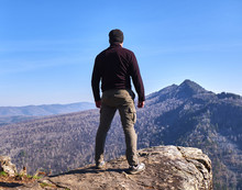 A Man Stands On The Edge Of A Rock